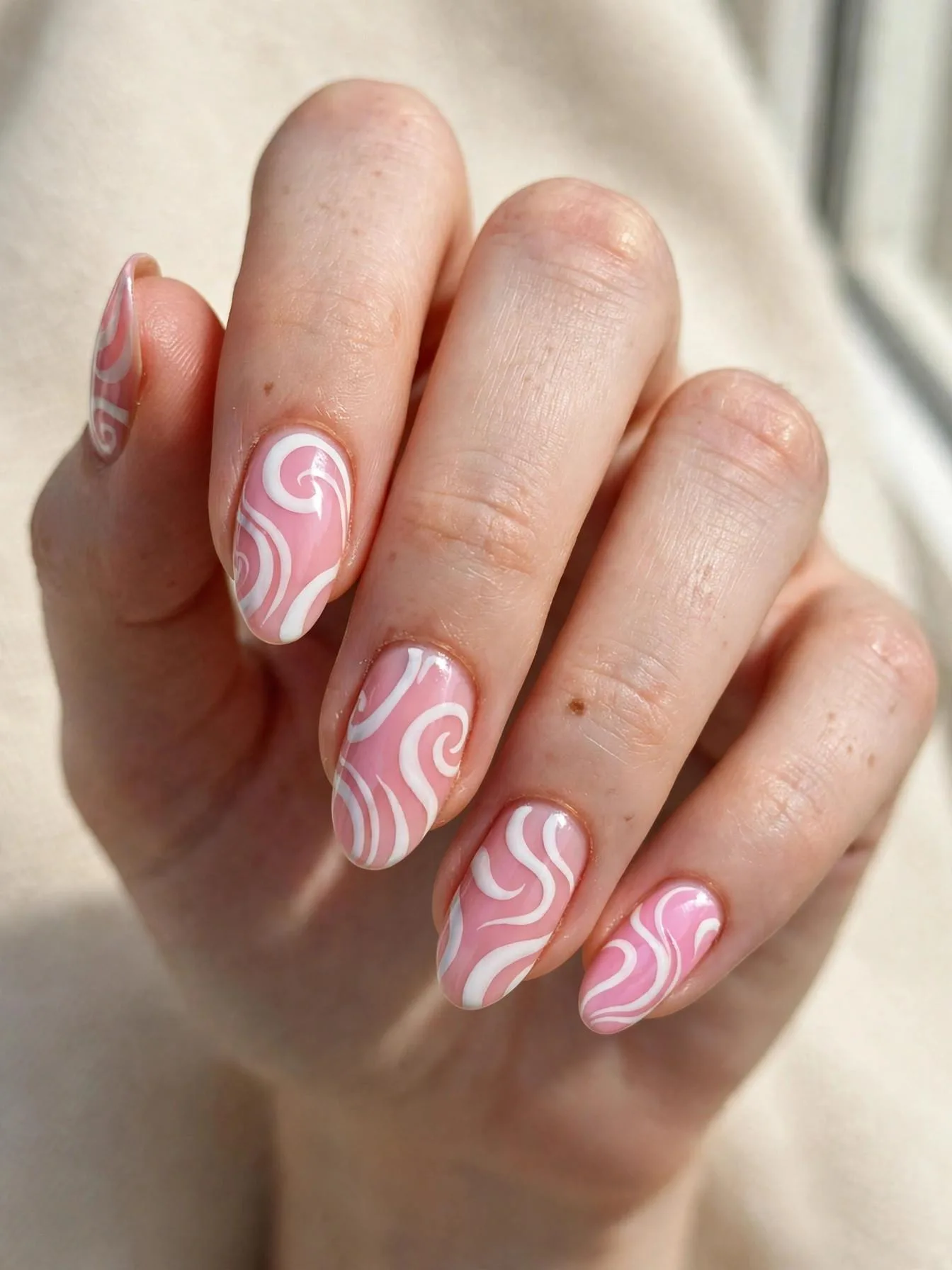 Soft pink almond nails with retro white wavy line art.