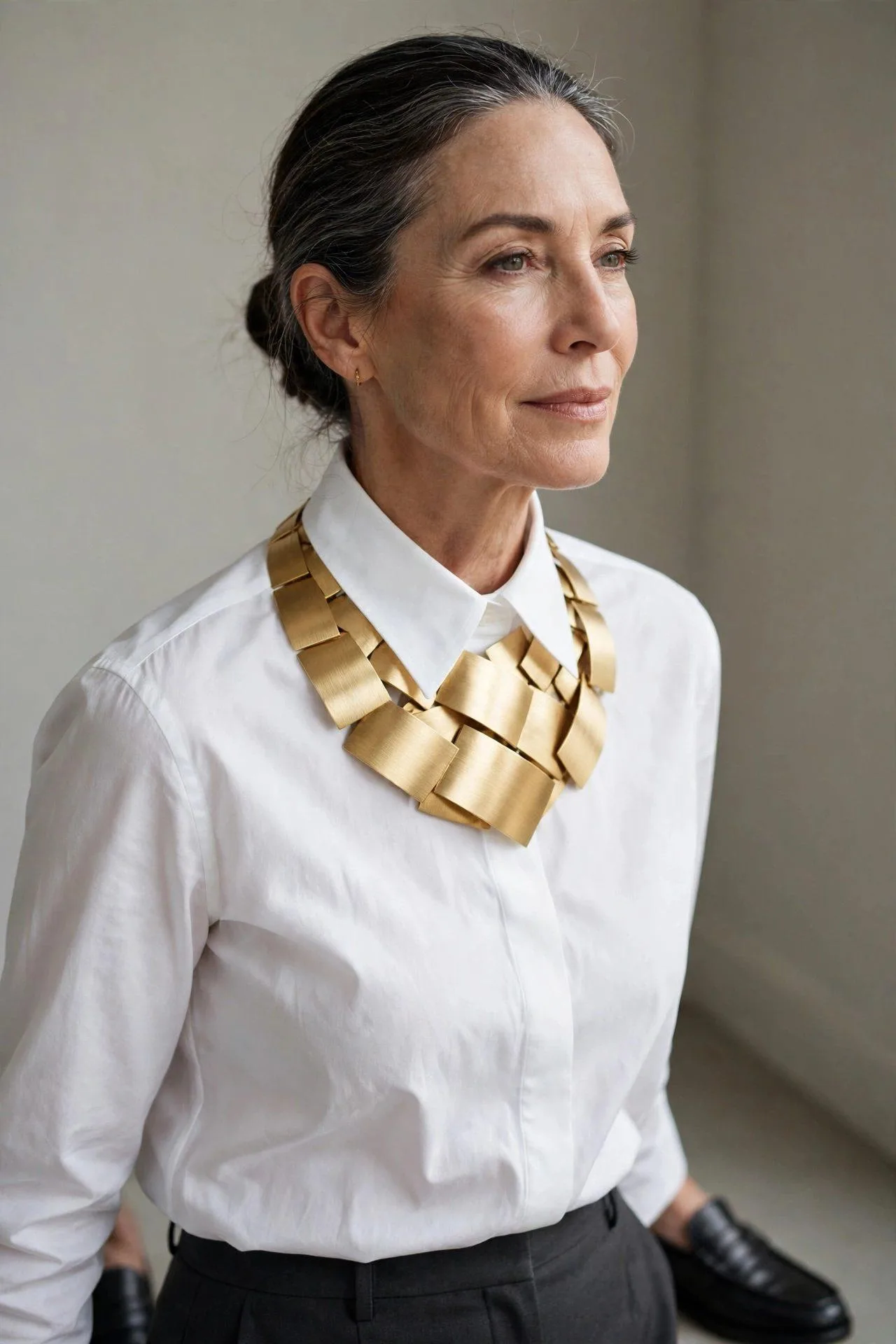 Modern bib necklace with brushed gold plates layered on a chambray collared shirt.