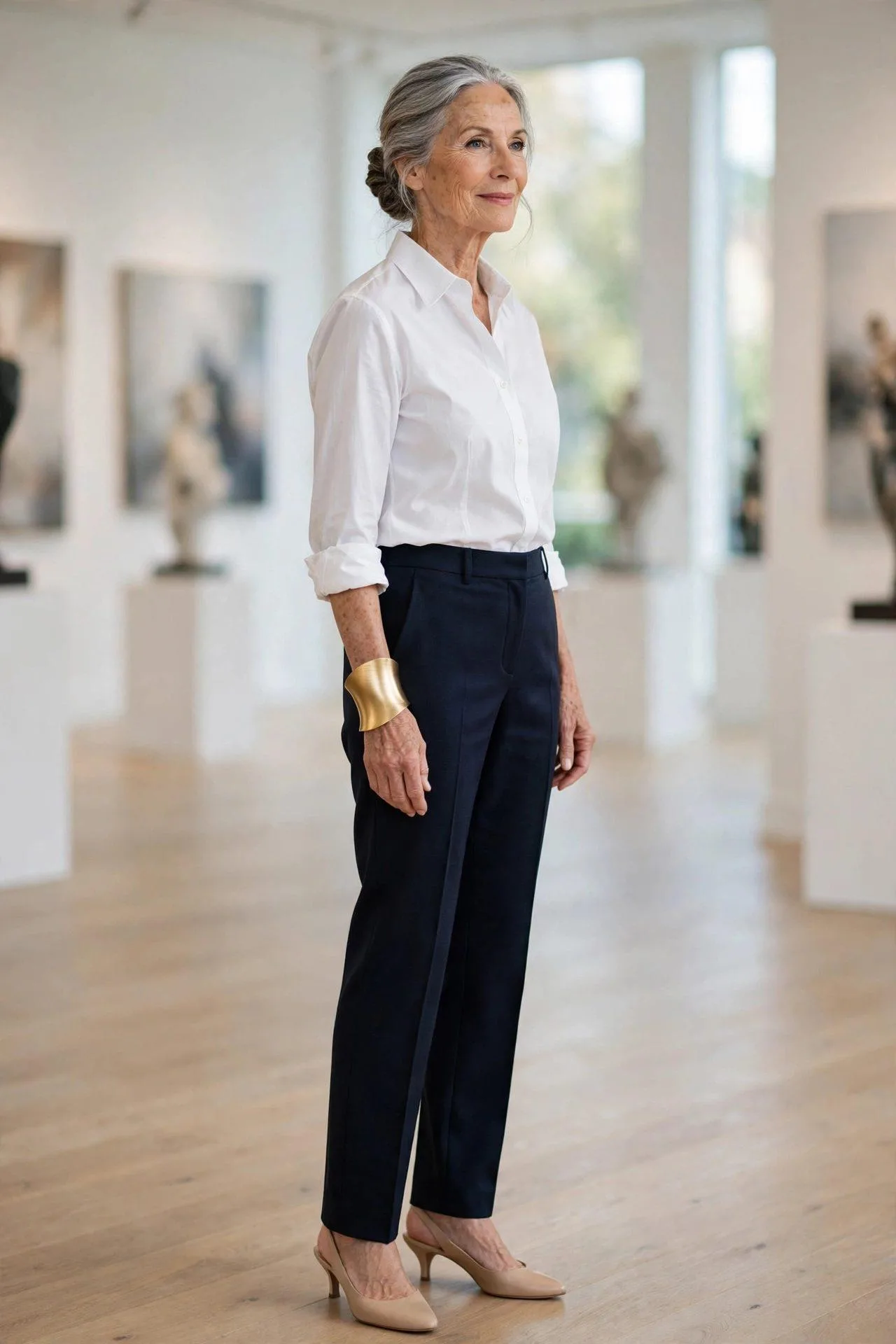 Silver-haired woman showcasing a broad hammered gold cuff above a white shirt cuff.