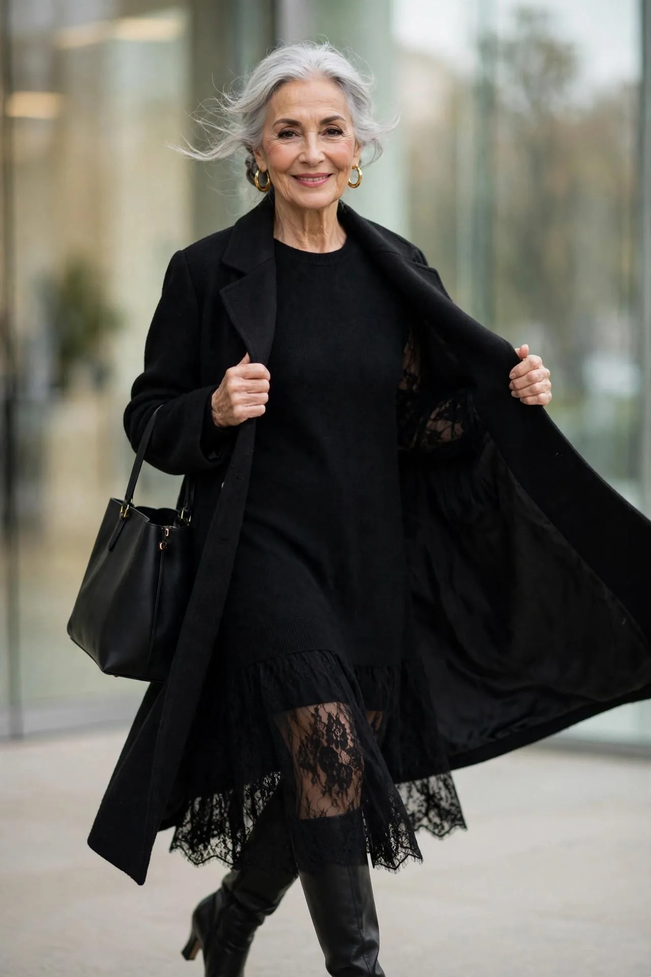 Mature woman in long black wool coat over black cashmere sweater dress with knee-high boots.