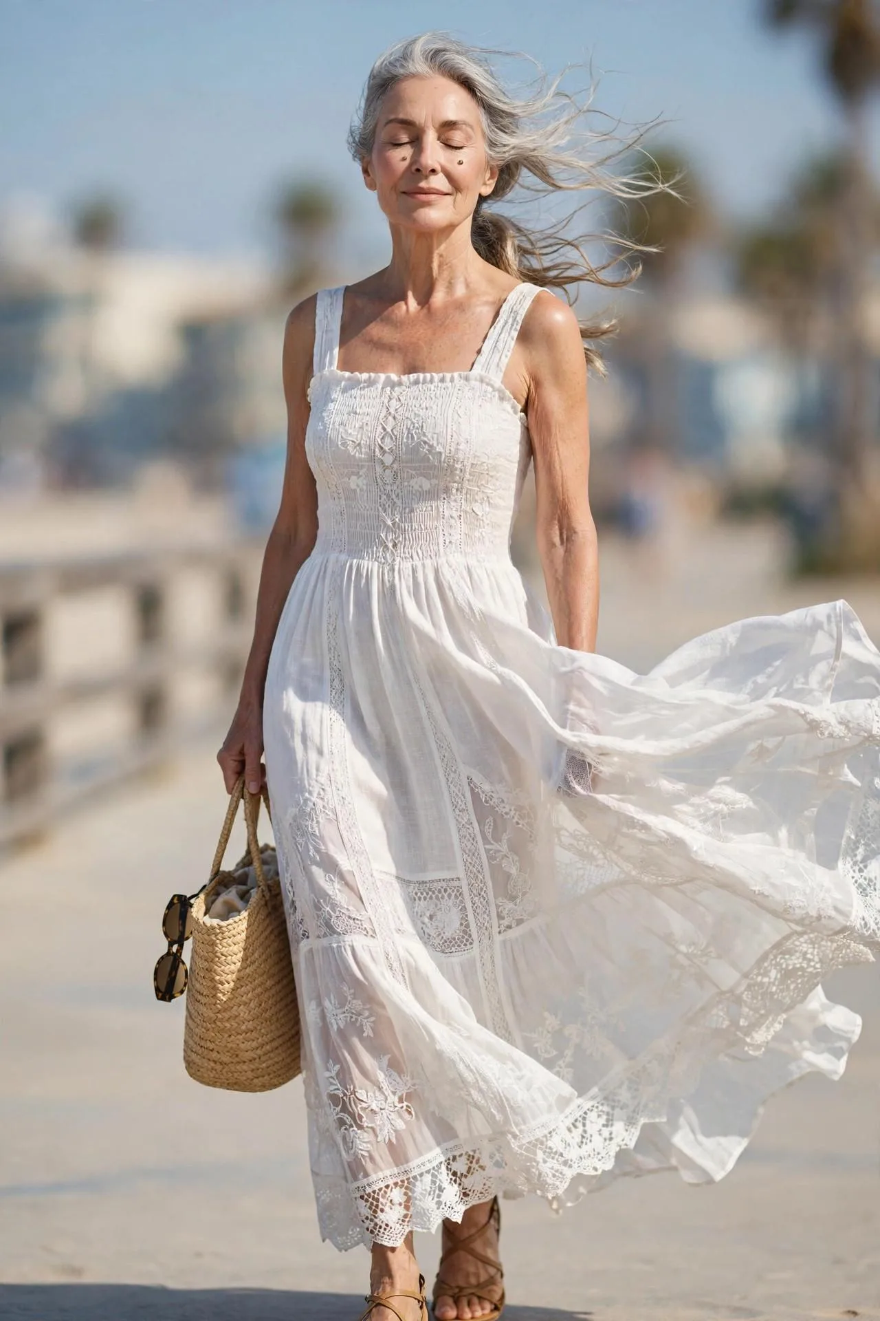 Serene 60-year-old woman with wind-lifted hair on a sunny beach boardwalk.