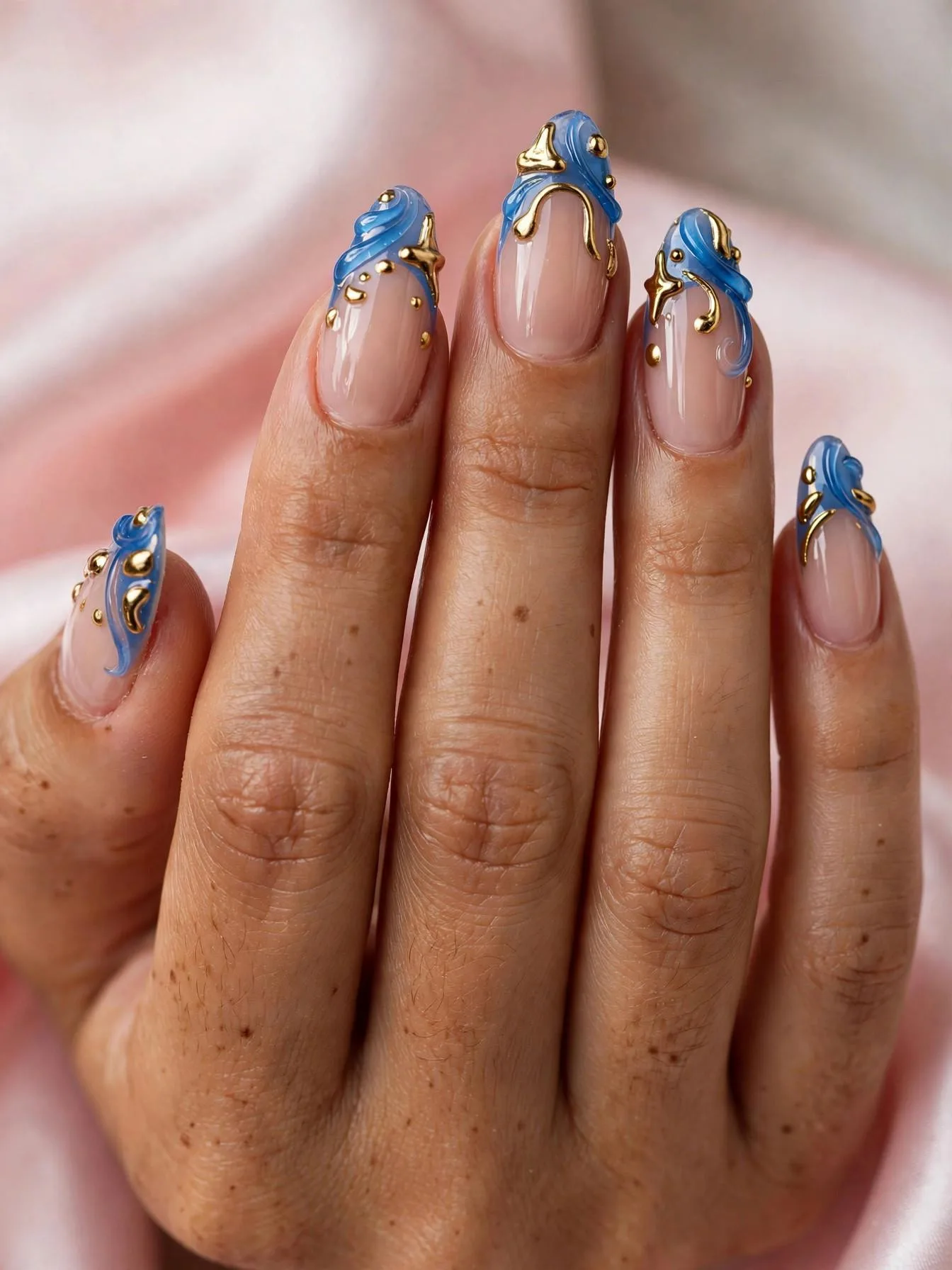 Long French nails with raised 3D gel accents in blue and gold.