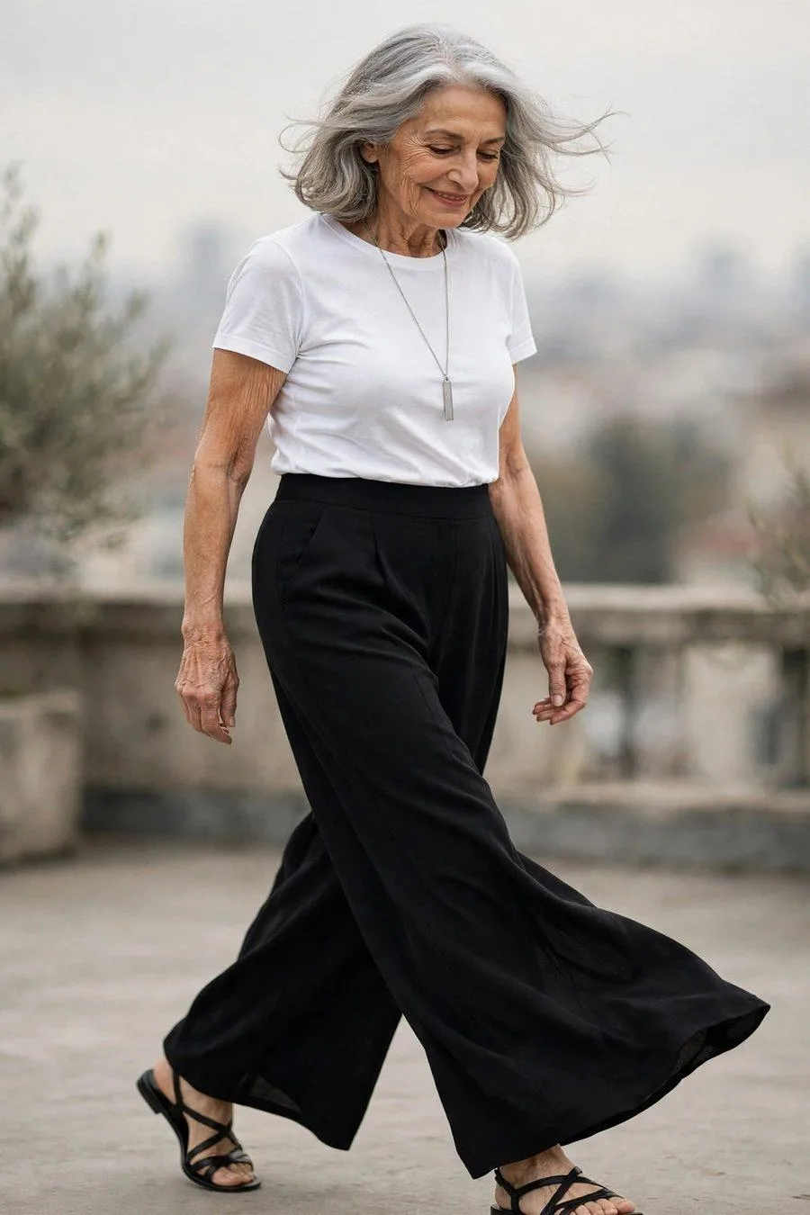 Confident mature woman in black palazzo pants and white tee at concert