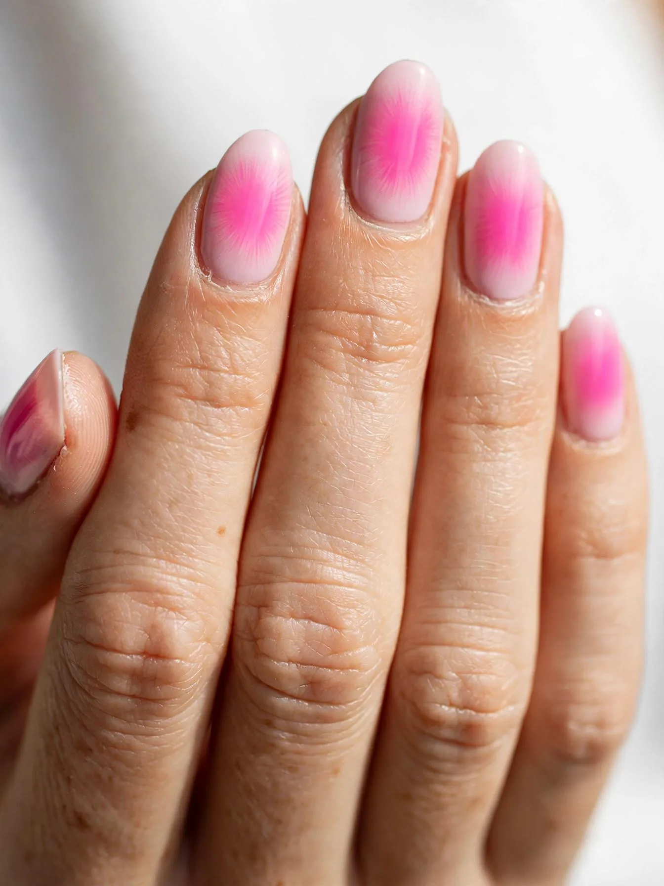 Almond nails with a radiant pink aura glowing from the center.