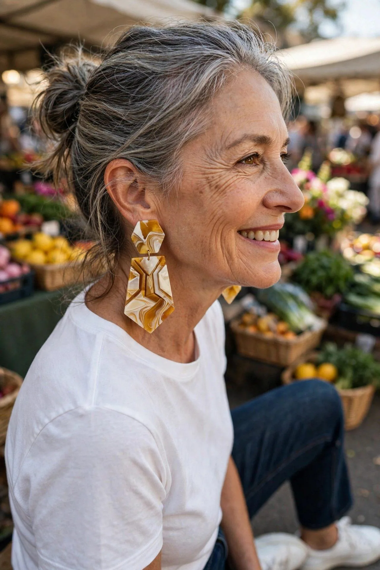 Architectural coral-red resin earrings, bold yet featherlight, on a smiling mature woman.