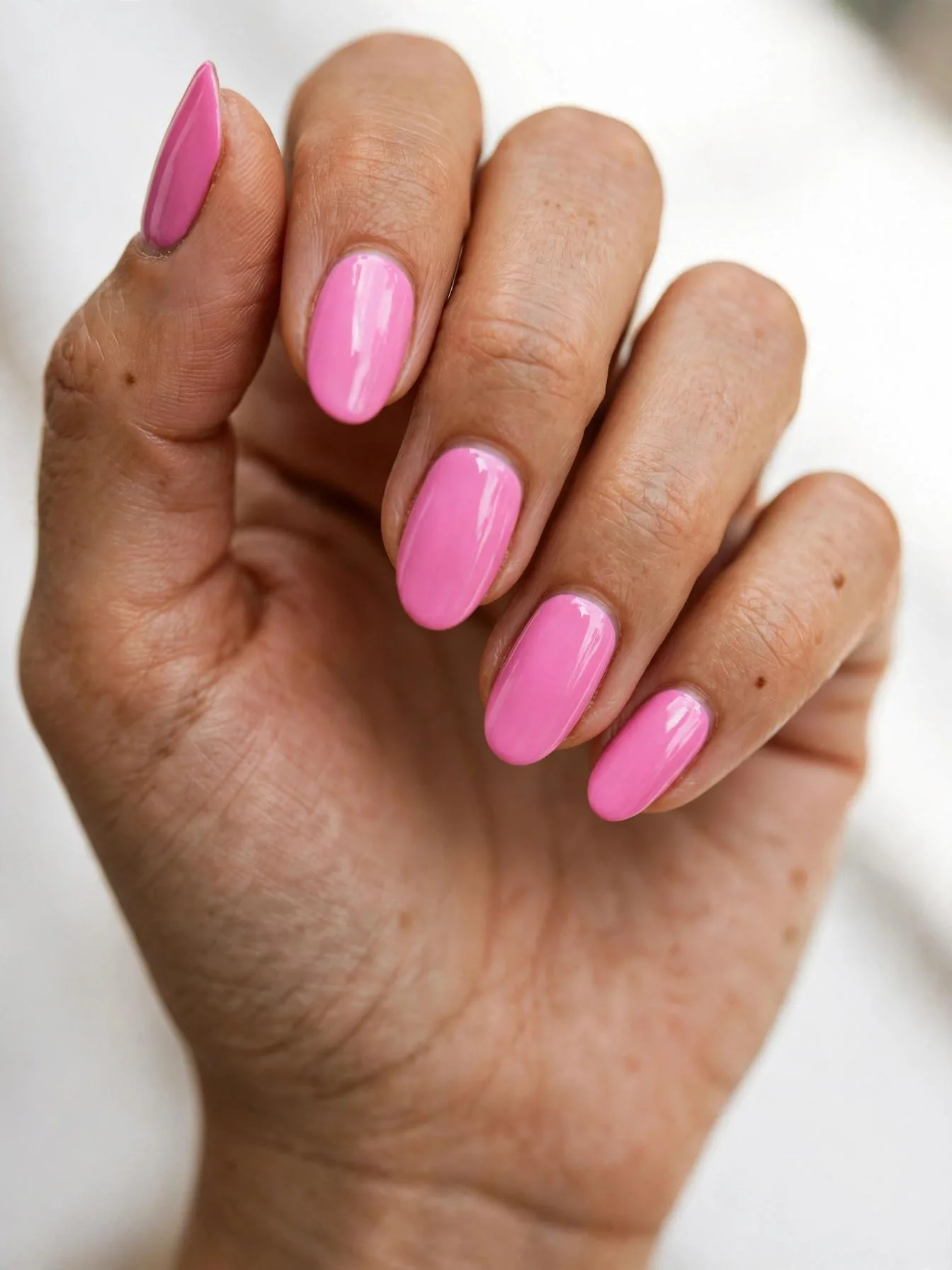 Bold bubblegum pink almond nails with a high-shine glossy coat.